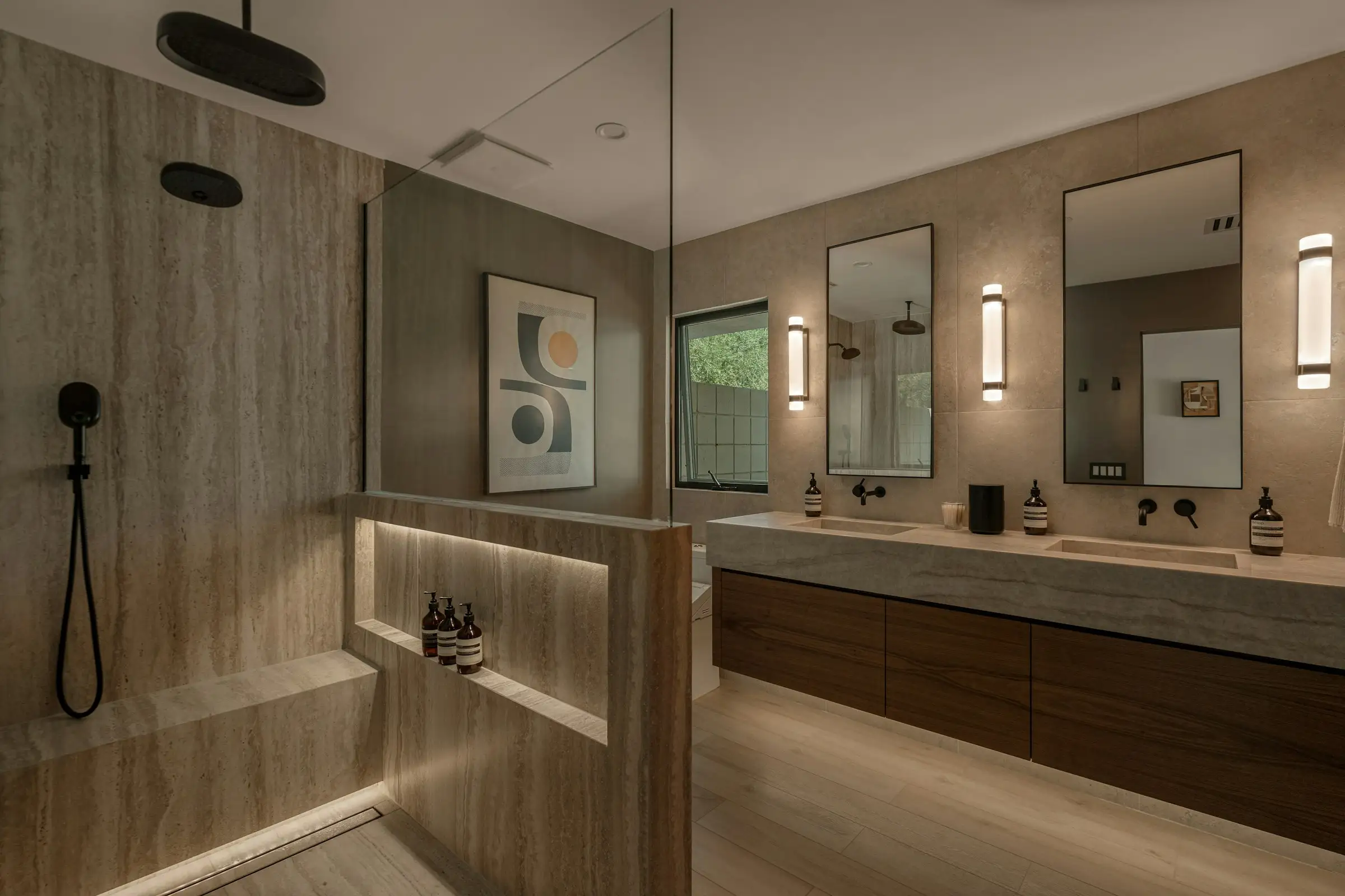 Baño de piedra con doble lavabo e iluminación cálida