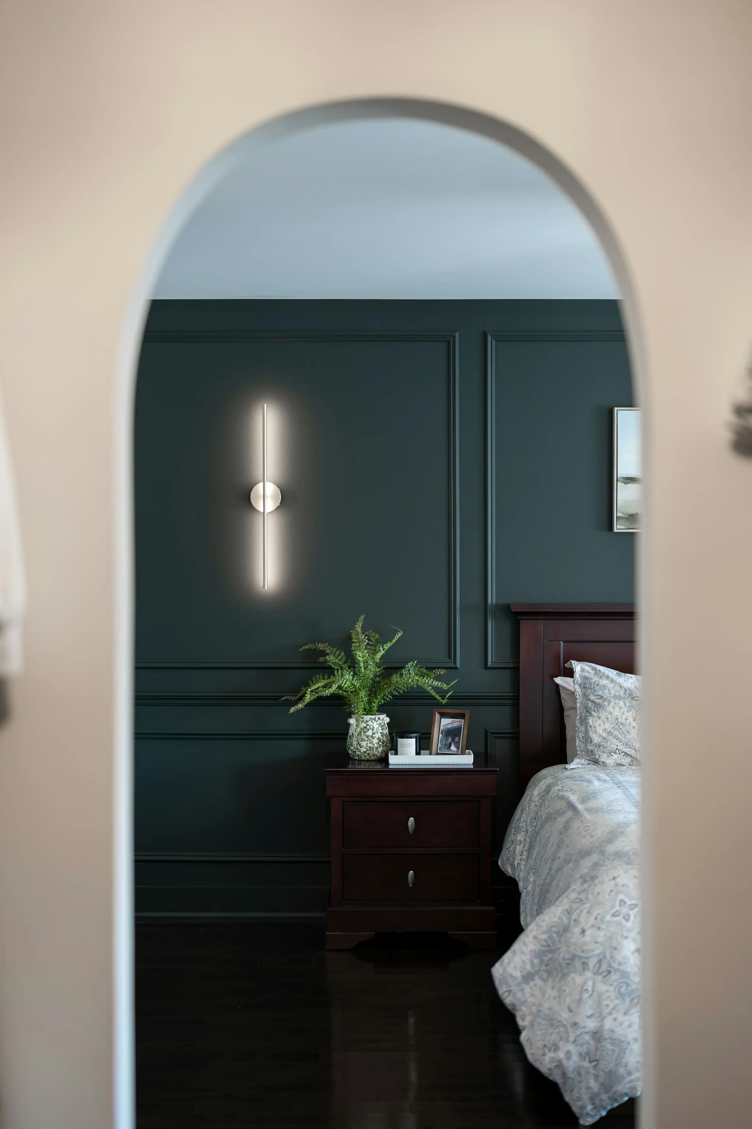 Dormitorio con pared verde oscuro y arco