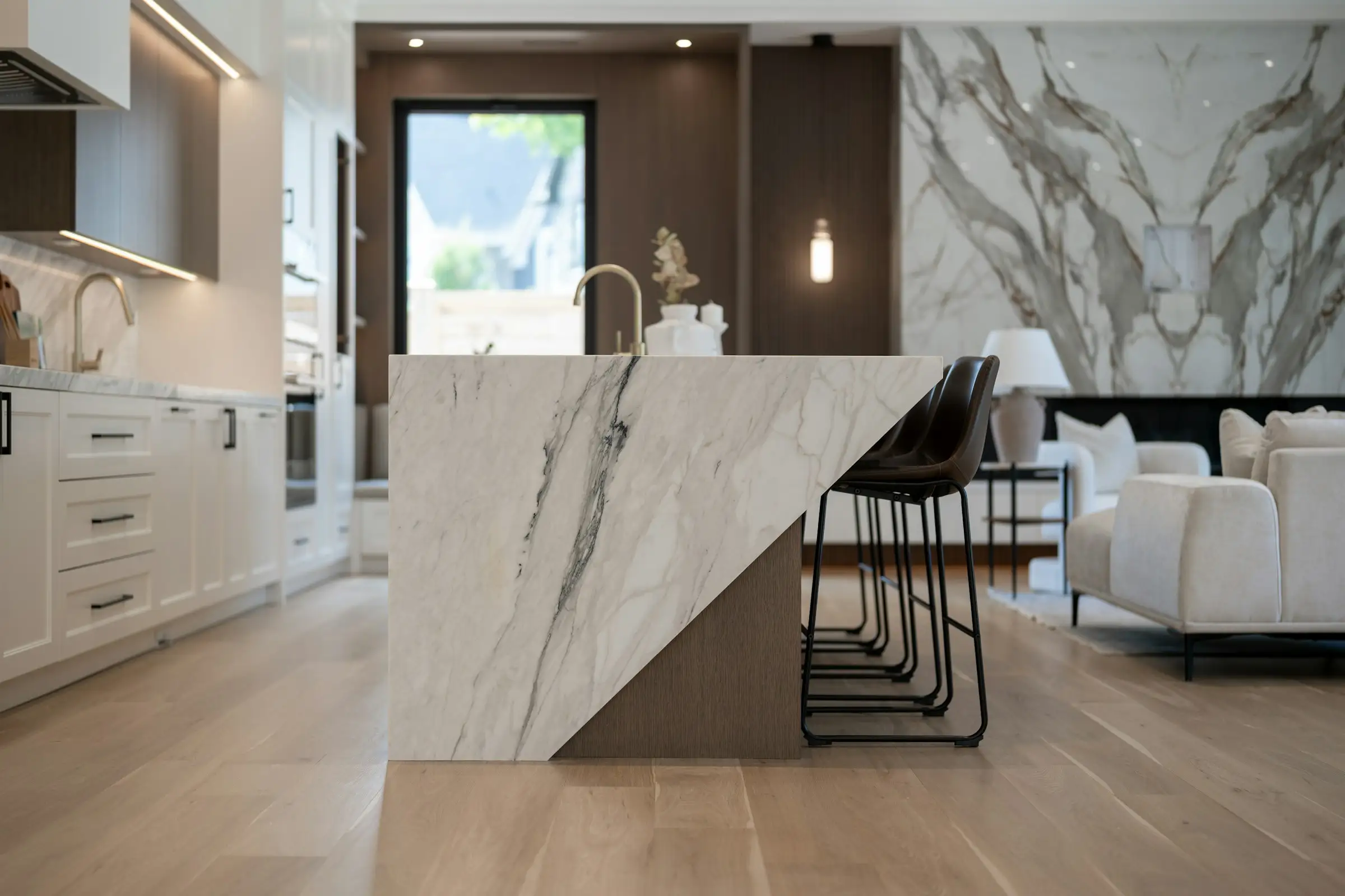 Cocina con gran isla de mármol veteado y taburetes